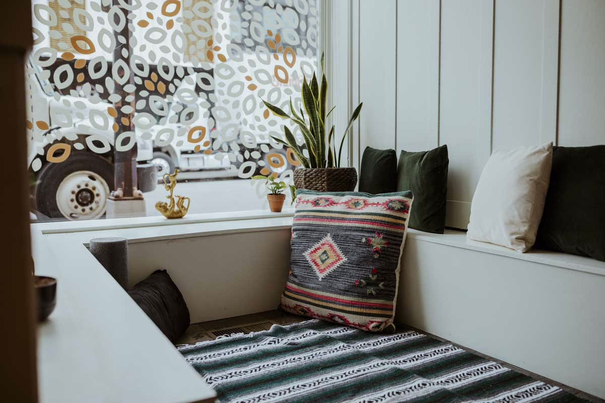 A sunlit window seat with cushions and plants in a Beyond Healing office