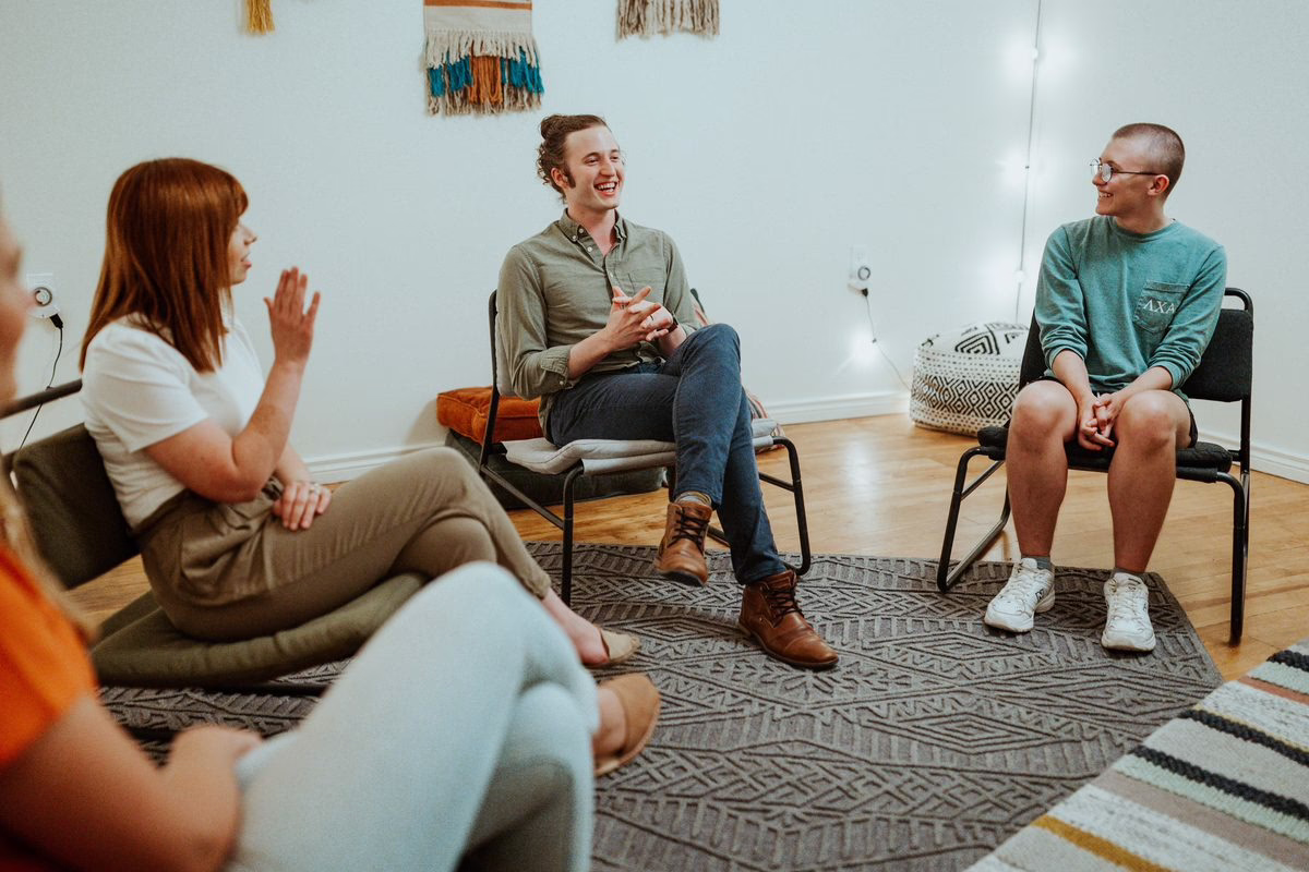 A therapy group talks and laughs together in a circle of chairs at Beyond Healing